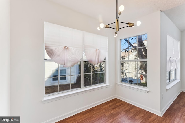 unfurnished dining area with a chandelier and hardwood / wood-style flooring