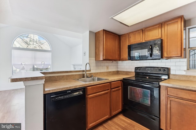 kitchen with kitchen peninsula, backsplash, sink, black appliances, and light hardwood / wood-style floors