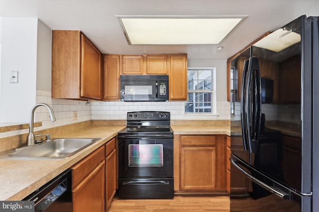 kitchen featuring sink, light hardwood / wood-style floors, backsplash, and black appliances