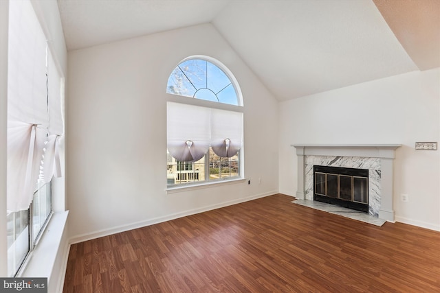 unfurnished living room featuring a wealth of natural light, hardwood / wood-style floors, a high end fireplace, and vaulted ceiling