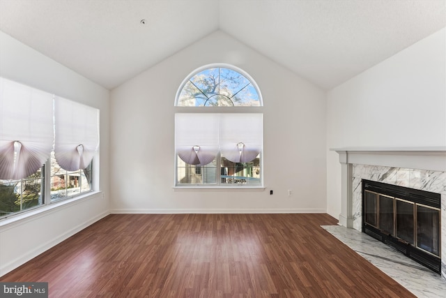 unfurnished living room featuring a high end fireplace, wood-type flooring, and vaulted ceiling