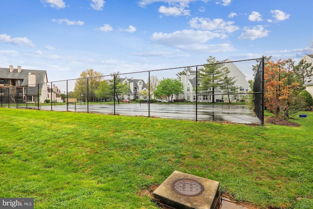 view of tennis court featuring a lawn