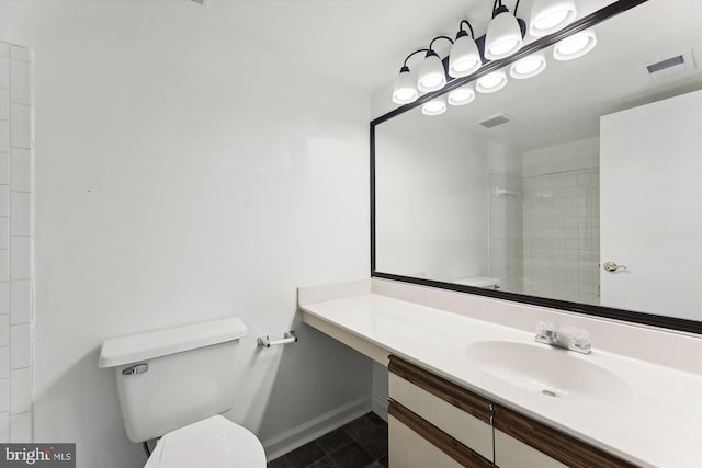 bathroom with vanity, toilet, and tiled shower