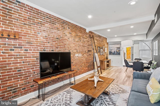 living room with beam ceiling, light wood-type flooring, crown molding, and brick wall