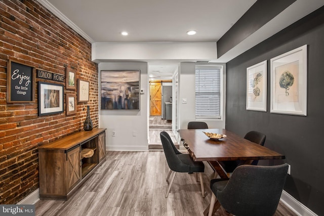 dining space with light wood-type flooring, crown molding, and brick wall