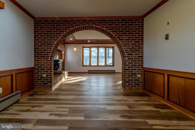 unfurnished living room featuring a fireplace, light hardwood / wood-style floors, crown molding, and a baseboard heating unit