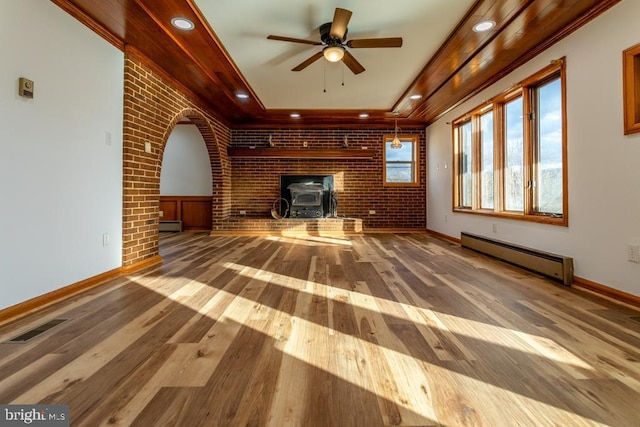 2520 Ridge Rd, Upper Tract, WV 26866 - unfurnished living room with a baseboard radiator, a wood stove, a ceiling fan, wood finished floors, and brick wall