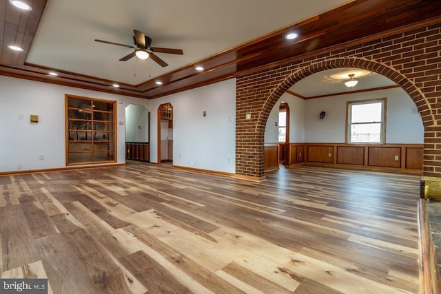 2520 Ridge Rd, Upper Tract, WV 26866 - unfurnished living room featuring arched walkways, ceiling fan, ornamental molding, wood finished floors, and wainscoting