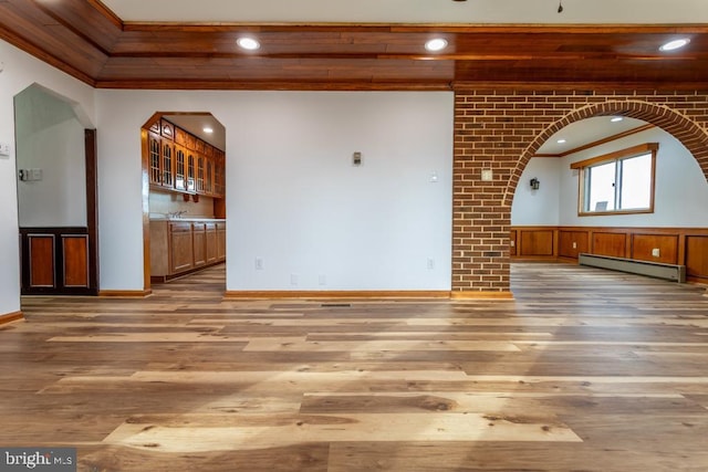 empty room with hardwood / wood-style floors, ornamental molding, and a baseboard heating unit