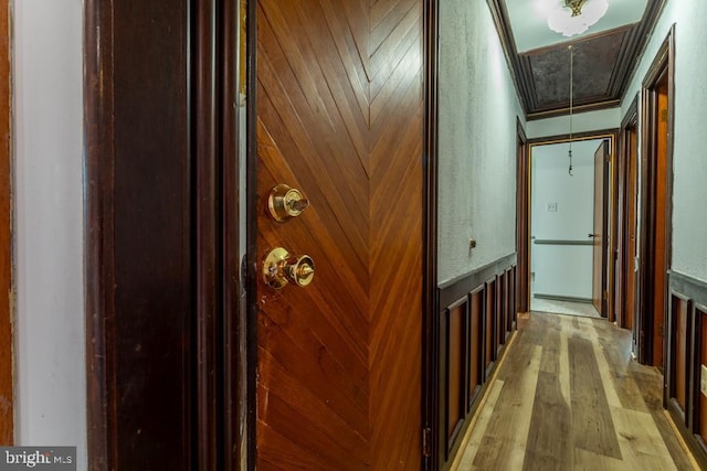 corridor featuring light hardwood / wood-style flooring, crown molding, and wood walls