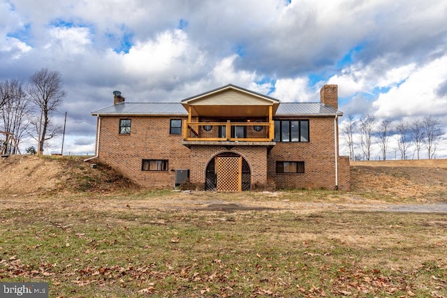 view of front of property featuring a front yard, a balcony, and central AC