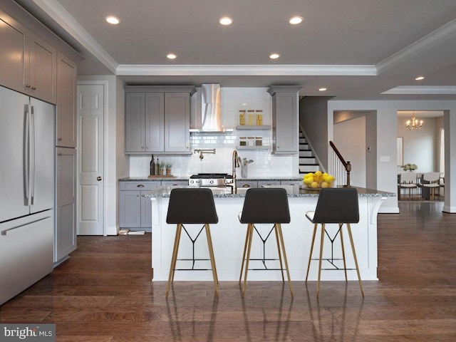 kitchen with built in refrigerator, a large island, stone counters, and a kitchen breakfast bar