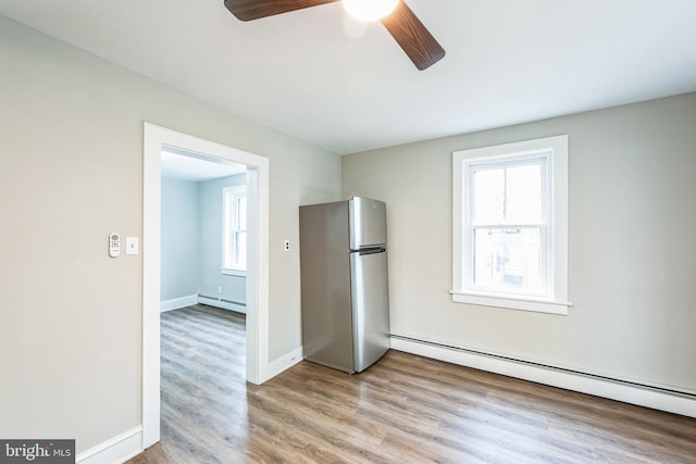 interior space featuring ceiling fan, light hardwood / wood-style flooring, and a baseboard heating unit