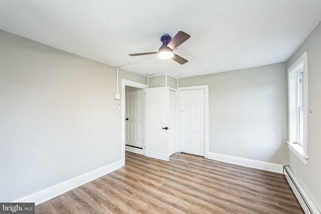 unfurnished bedroom with ceiling fan, a closet, light hardwood / wood-style floors, and a baseboard heating unit