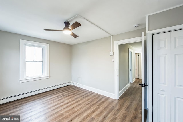 empty room featuring hardwood / wood-style floors, ceiling fan, and a baseboard heating unit