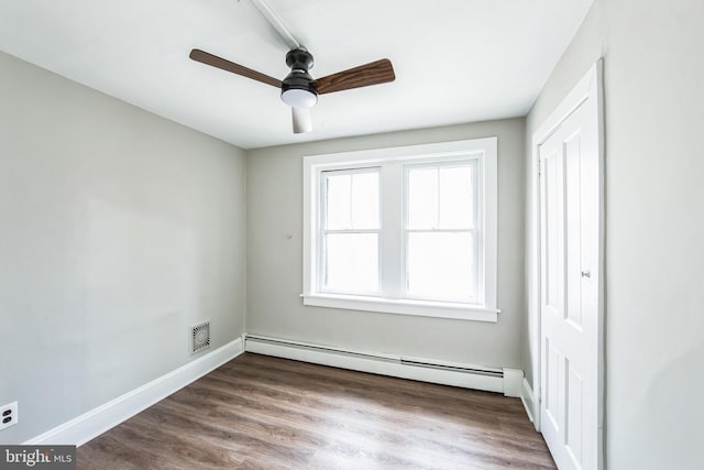 empty room featuring ceiling fan, hardwood / wood-style floors, and a baseboard heating unit