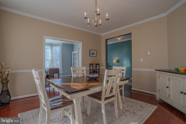 dining space with wood-type flooring, crown molding, and a notable chandelier