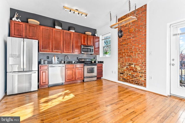 kitchen with backsplash, sink, light wood-type flooring, and stainless steel appliances