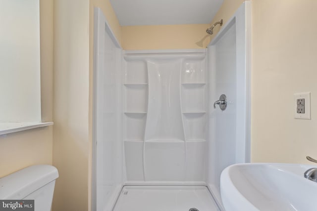 bathroom featuring toilet, walk in shower, and sink