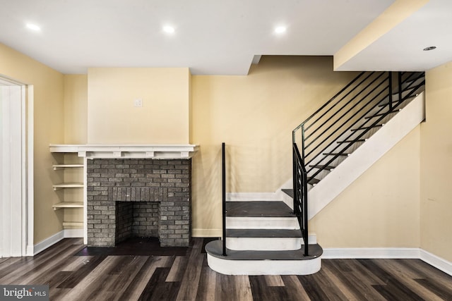 stairway with a fireplace and wood-type flooring