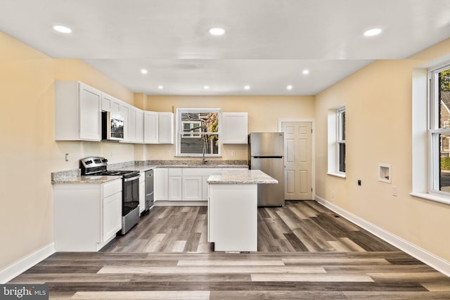 kitchen with white cabinets, a kitchen island, dark hardwood / wood-style flooring, and stainless steel appliances