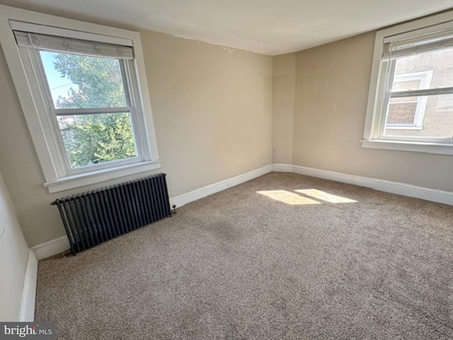 empty room featuring carpet flooring, radiator, and a healthy amount of sunlight