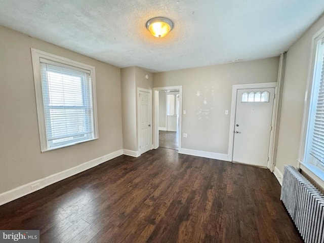 foyer entrance featuring dark hardwood / wood-style flooring, a textured ceiling, and radiator