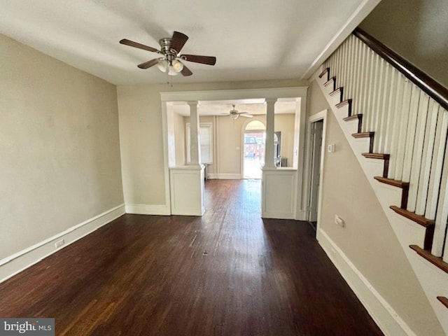 spare room featuring ceiling fan, dark wood-type flooring, and decorative columns