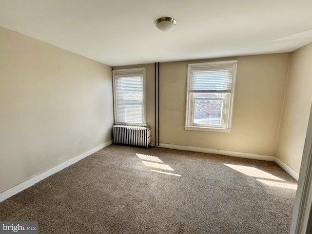 spare room featuring carpet flooring, plenty of natural light, and radiator heating unit