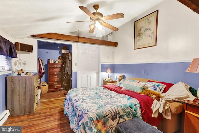 bedroom with lofted ceiling, ceiling fan, baseboard heating, wood-type flooring, and a closet