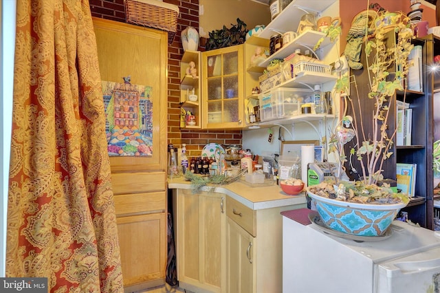 kitchen featuring light brown cabinets and brick wall