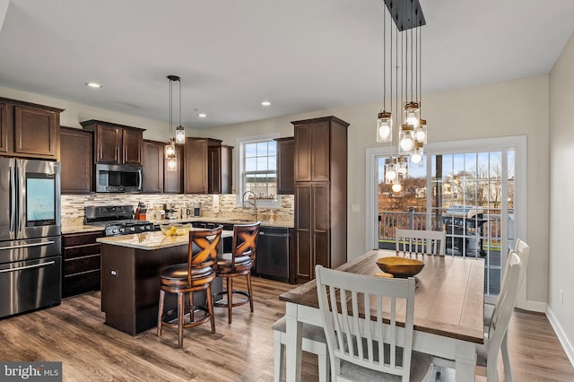 kitchen featuring hardwood / wood-style floors, a kitchen island, black appliances, and decorative light fixtures