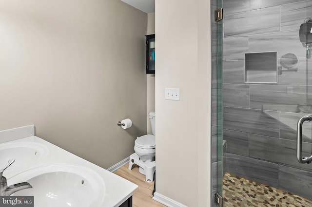 bathroom with a shower with door, vanity, hardwood / wood-style floors, and toilet