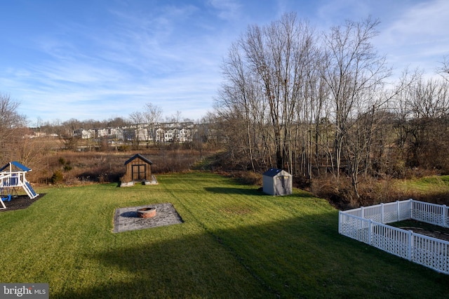 view of yard featuring a storage shed, a playground, and an outdoor fire pit