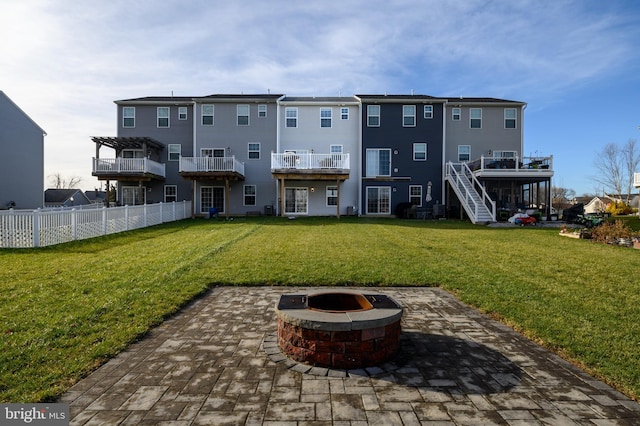 rear view of house featuring a fire pit, a patio, and a lawn