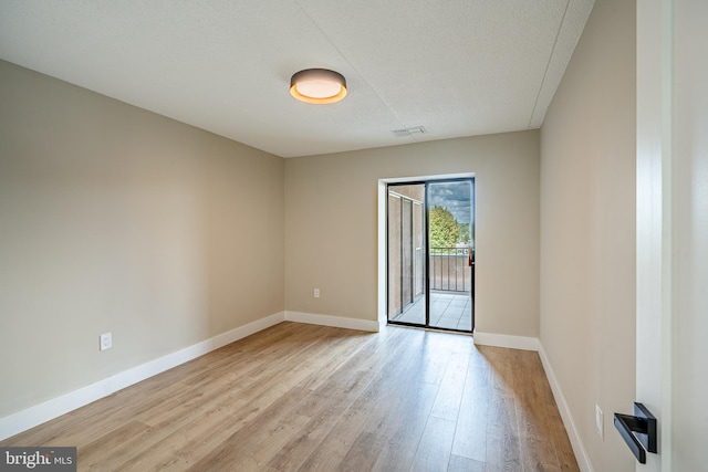 spare room with a textured ceiling and light wood-type flooring