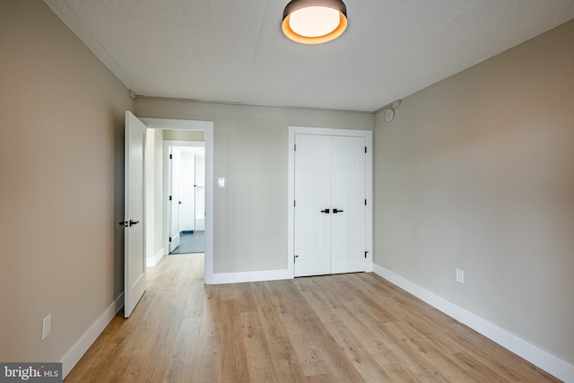 unfurnished bedroom with light wood-type flooring, a textured ceiling, and a closet