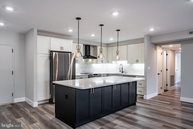 kitchen featuring white cabinetry, a kitchen island, wall chimney exhaust hood, and sink