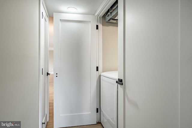 clothes washing area with washer / clothes dryer and light hardwood / wood-style flooring