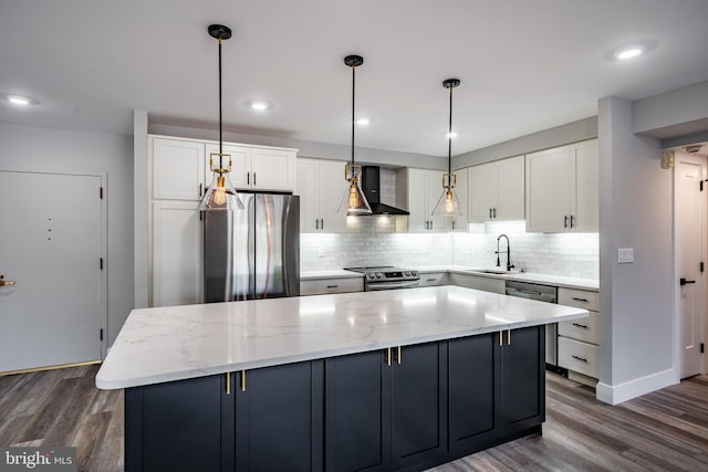 kitchen with appliances with stainless steel finishes, sink, white cabinetry, and wall chimney range hood