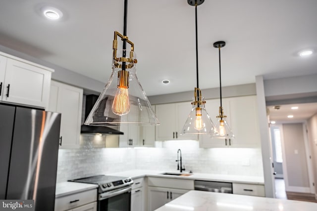 kitchen featuring backsplash, white cabinets, hanging light fixtures, sink, and appliances with stainless steel finishes