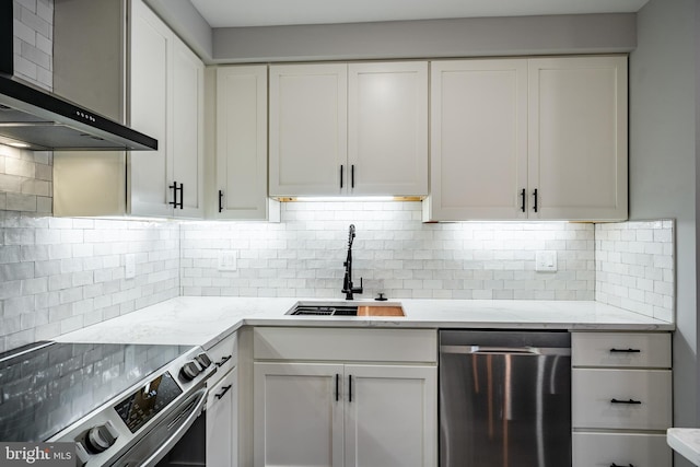 kitchen with sink, wall chimney exhaust hood, decorative backsplash, white cabinets, and appliances with stainless steel finishes