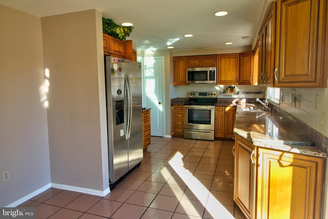 kitchen with a healthy amount of sunlight, light tile patterned floors, sink, and appliances with stainless steel finishes