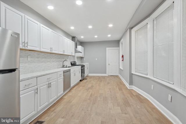 kitchen featuring sink, decorative backsplash, light hardwood / wood-style floors, white cabinetry, and stainless steel appliances