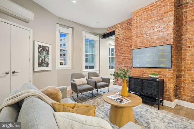 living room featuring hardwood / wood-style flooring, a wall unit AC, and brick wall