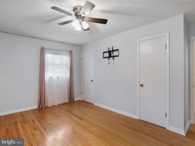 empty room featuring a textured ceiling, light wood-type flooring, and ceiling fan