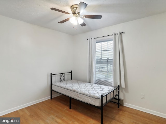 bedroom with ceiling fan, wood-type flooring, and a textured ceiling