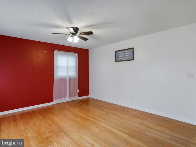 empty room featuring ceiling fan, light wood-type flooring, and a textured ceiling