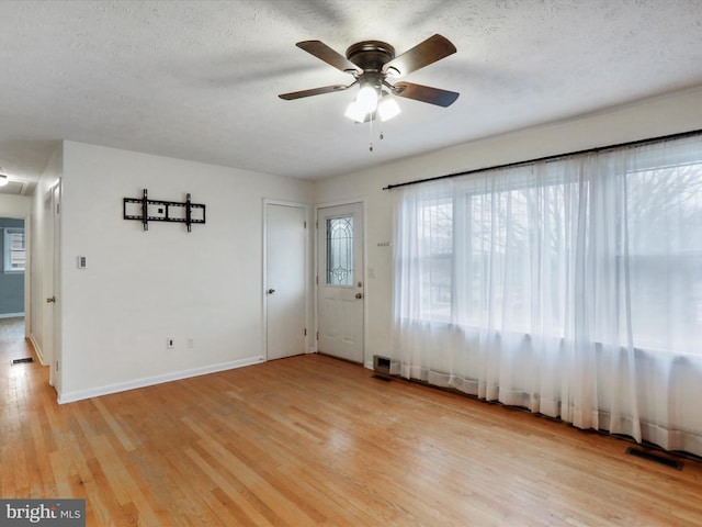 spare room featuring a textured ceiling, light wood-type flooring, and ceiling fan