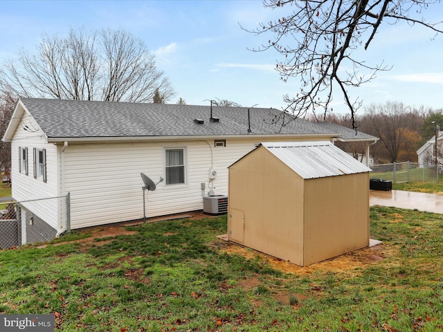 rear view of house featuring a yard, central AC, and a storage unit